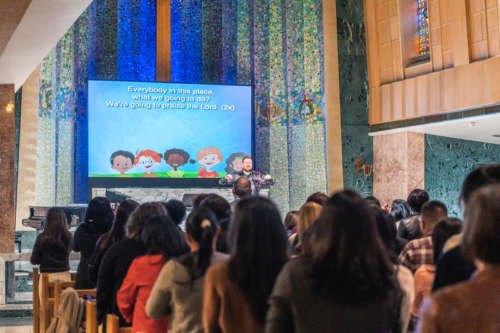 A man leads a congregation in worship meant for children